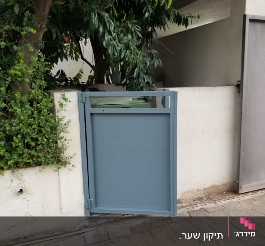 שער מתכת כחול פתוח ליד קיר לבן